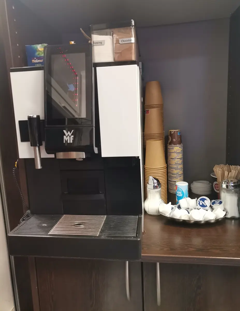 Kaffeeautomat mit Bechern, Milch und Zubehör im Laden