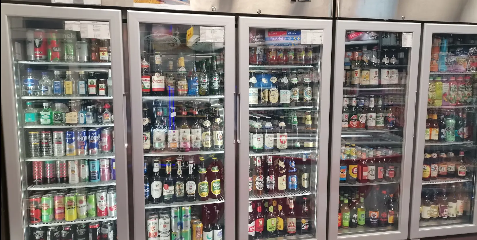 Getränkekühlschränke mit Bierflaschen, Dosen und Limonaden hinter Glastüren